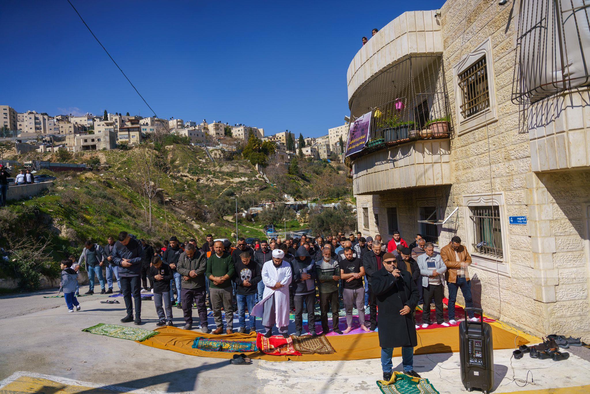 مواطنون يؤدون صلاة الجمعة أمام بناية مهددة بالهدم في حي واد قدوم ببلدة سلوان بالقدس المحتلة (تصوير: وفا)